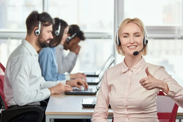 Mujer rubia trabajando en la oficina mostrando el pulgar hacia arriba . — Foto de Stock