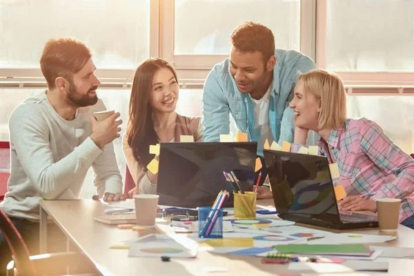 Gente de negocios en tela casual sonriendo juntos mientras miran el portátil en la oficina . — Foto de Stock