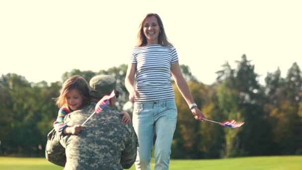 Rückseite: US-Soldat in Tarnkleidung umarmt Familie. — Stockvideo