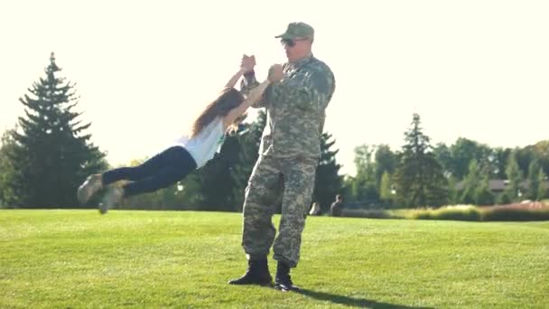 Soldat i camoubackgrounde snurrar hans dotter runt i parken. — Stockvideo