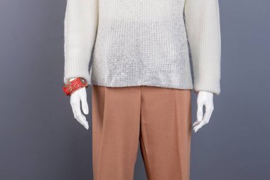 Aptal beyaz kazak ve kahverengi pantolon.