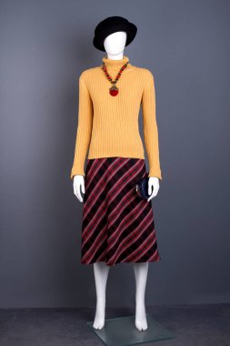 Siyah şapka, kazak ve çizgili etek.