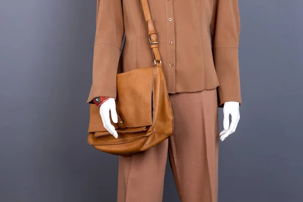 Mannequin with brown clothes and bag.