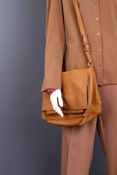 Female mannequin with fashion brown handbag.