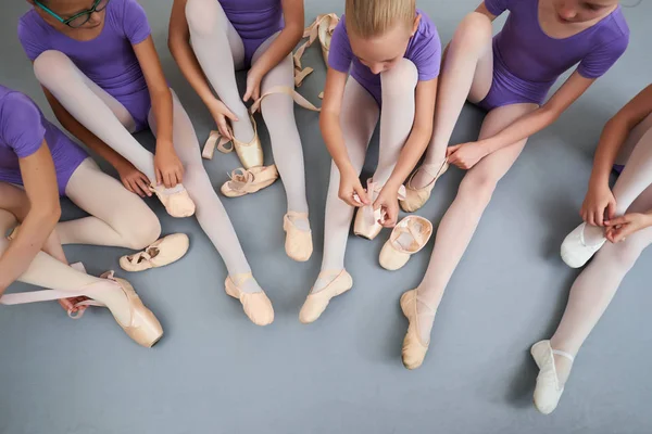 Group of ballerinas put on slippers, top view.