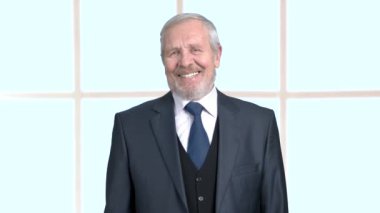 Yaşlı işadamı gülüyor, arka plan bulanık.