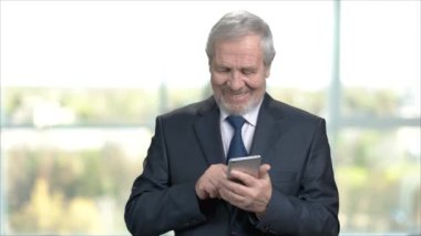 Smartphone kullanarak yaşlı gülümseyen iş adamı.