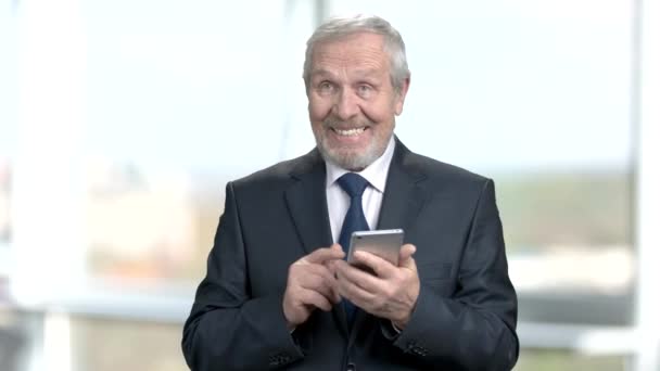 Удовлетворенный пожилой бизнесмен со смартфоном . — стоковое видео
