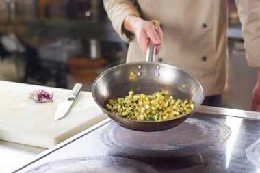 Kızartma tavası dilimlenmiş sebze ile tutarak Şef.