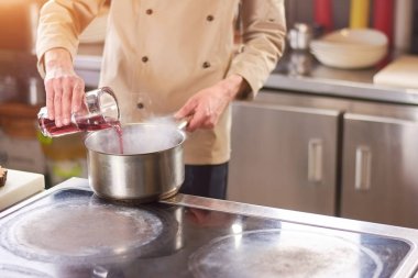 Şef kırmızı sos güveç içinde dökme.