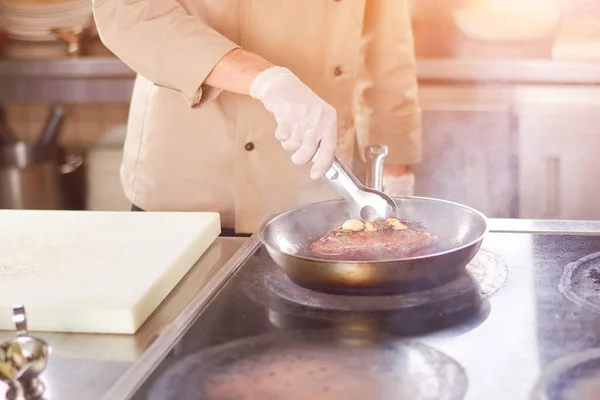 Шеф-повар жарит мясо с чесноком . — стоковое фото