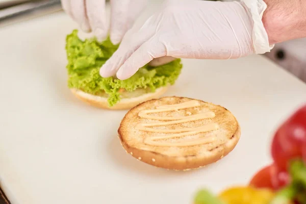 Chef agregando hoja de lechuga en hamburguesa . —  Fotos de Stock