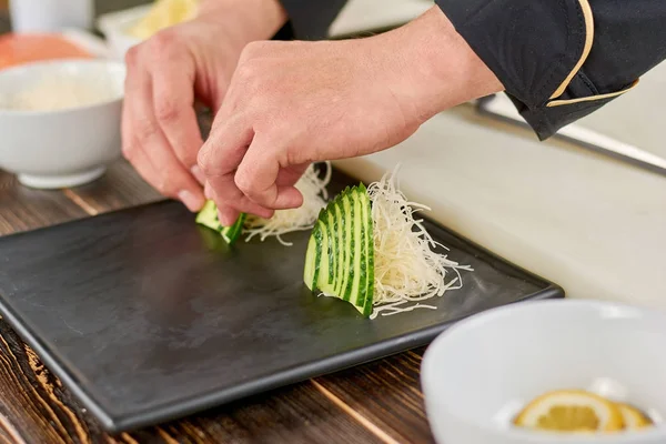 Шеф-повар украшает тарелку нарезанным огурцом . — стоковое фото