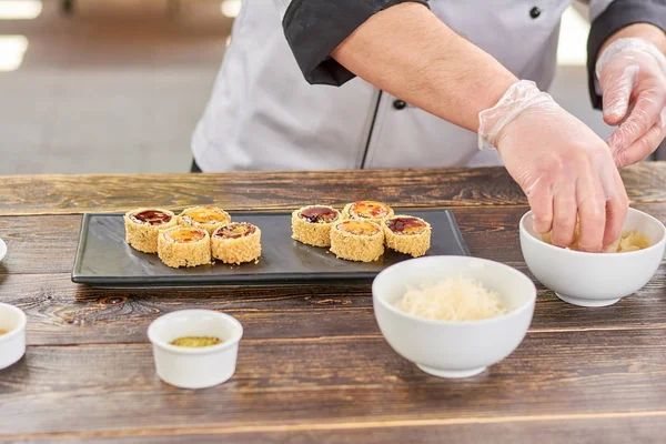 Chef hands putting ginger from bowl.