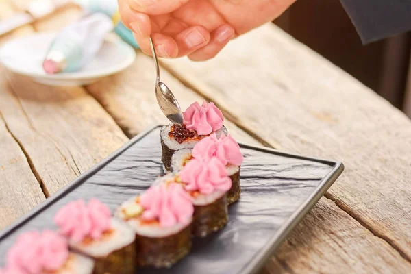 Chef hand adding caviar on sushi rolls. — Stock Photo, Image