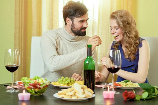 Guy feeding grape to girl.