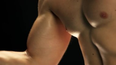 Gömleksiz adam kol egzersizi yapıyor..