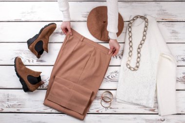 Eller masanın üzerinde kahverengi pantolon koymak.