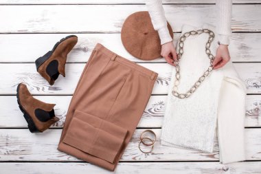 Zincir kolye üzerinde beyaz yün kazak giy eller.