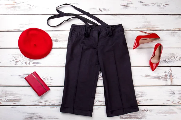 Zwarte broek met bretels en rode accessoires. — Stockfoto
