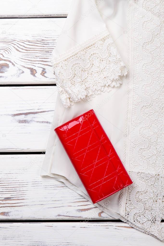 White lace blouse and red wallet, close up.