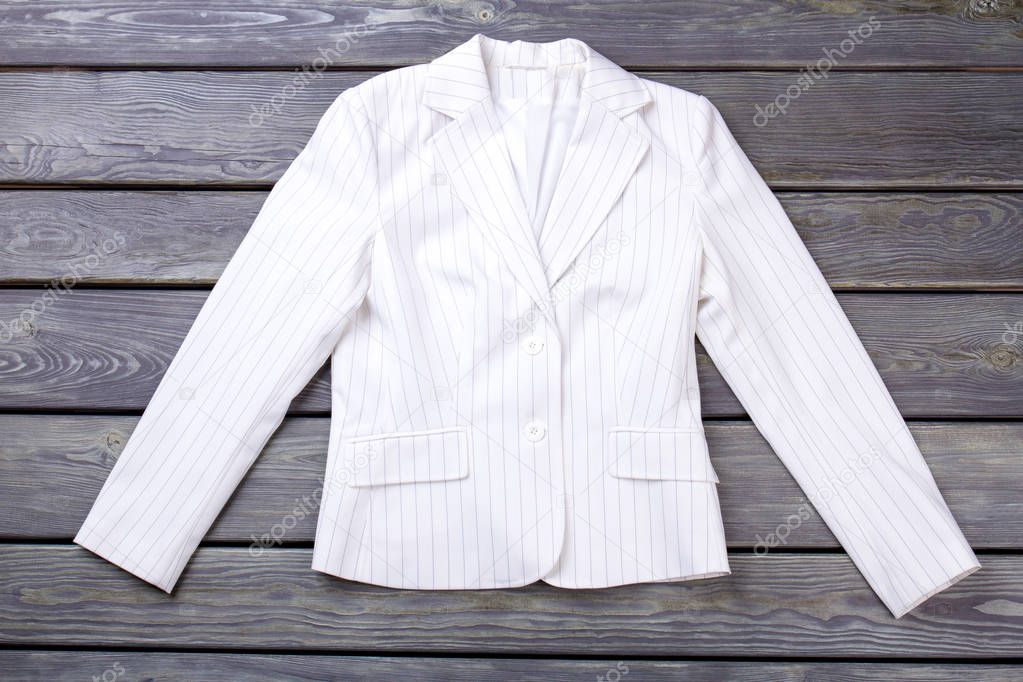 Flat lay white jacket on dark surface background.