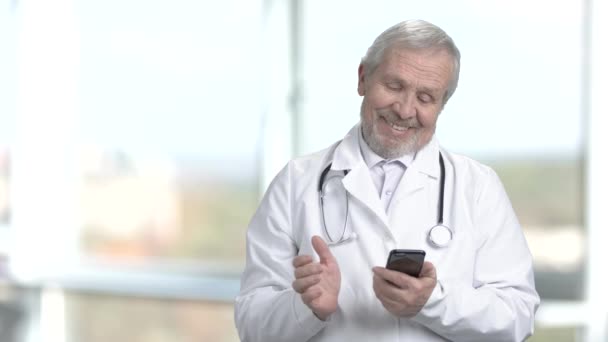 Médico sonriente usando su teléfono inteligente . — Vídeo de stock