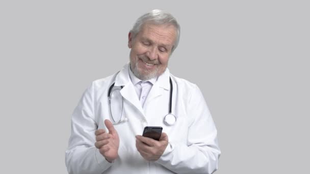 Médico feliz con smartphone, fondo gris . — Vídeos de Stock