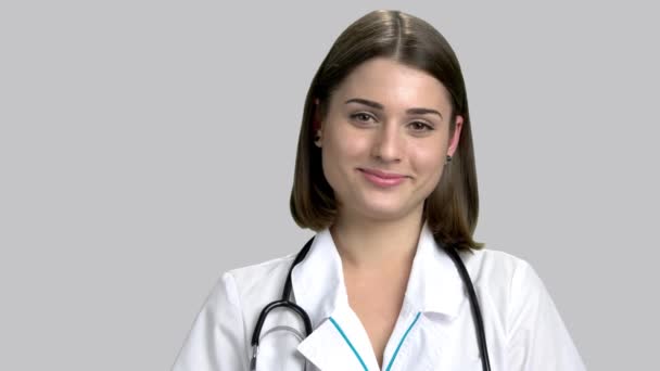 Joven médico sonriente sobre fondo gris . — Vídeo de stock