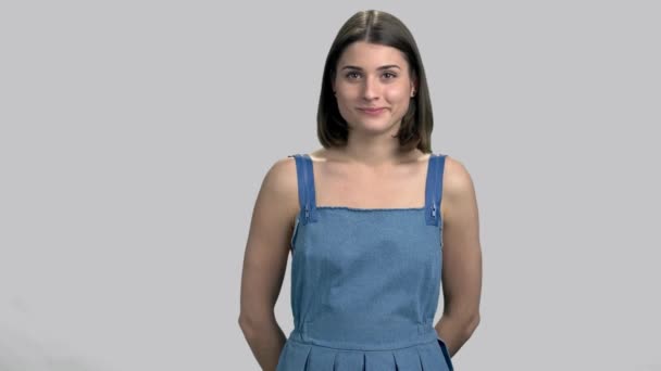 Cheerful girl is thinking on gray background. — Stock Video