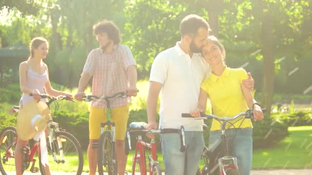 Par av unga cyklister kyssar utomhus. — Stockvideo