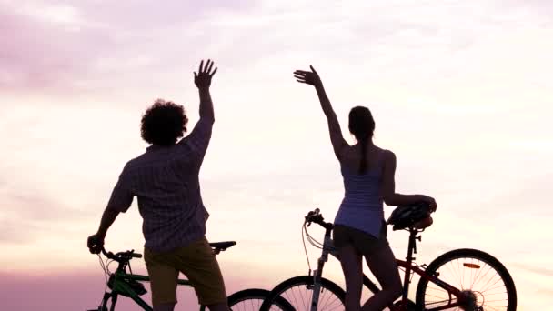 Jeune couple avec vélos au coucher du soleil . — Video