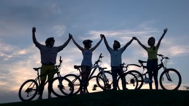 Jeunes cyclistes tenant la main au coucher du soleil . — Video