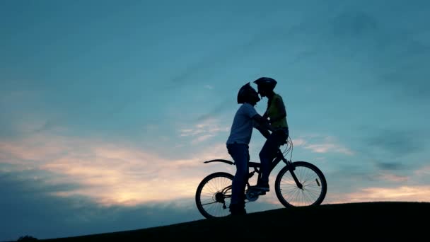 Kyss av romantiska ungt par på cyklar mot solnedgången. — Stockvideo