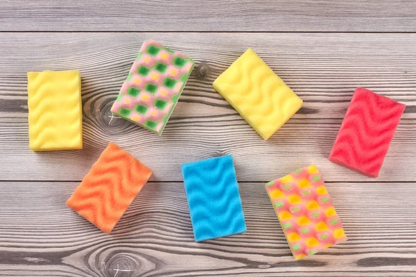 Multicolored kitchen sponges, wooden background.