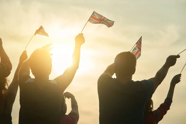 Young people waving british flags, back view.