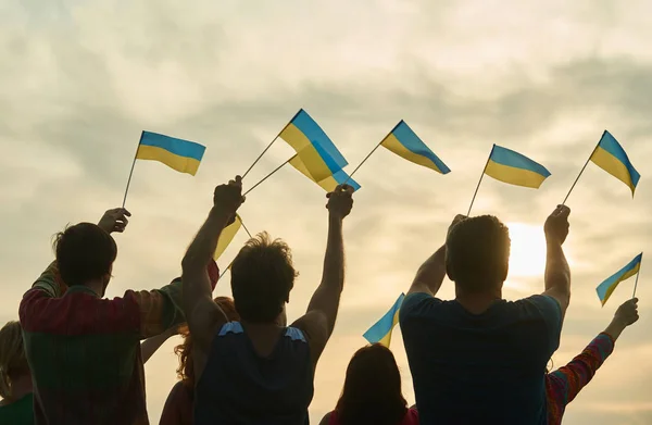 Молодь махає українськими прапорами, вид ззаду . — стокове фото