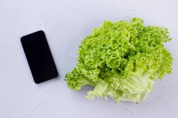 纹理背景下的生菜和智能手机. — 图库照片