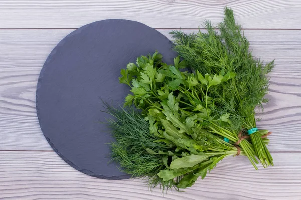 Bunches of fresh herbs on round slate.