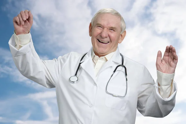 Vieux médecin masculin riant à haute voix avec les mains en l'air . — Photo