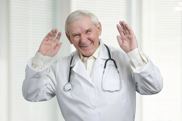 Médico mayor riendo duro con las manos levantadas . — Foto de Stock