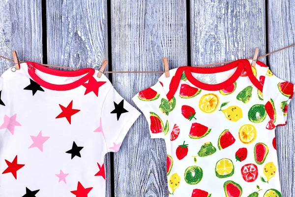 Çocuklar modern giysiler ipte asılı.