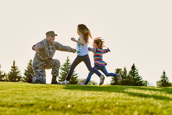 Reunion of soldier and daughters outdoor on the lawn.