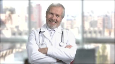 Arka plan bulanık üzerinde gülümseyen kıdemli doktor.