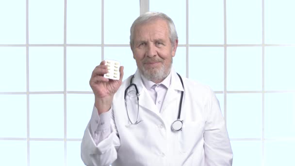 Oudere arts glimlachend met blister van pillen. — Stockvideo