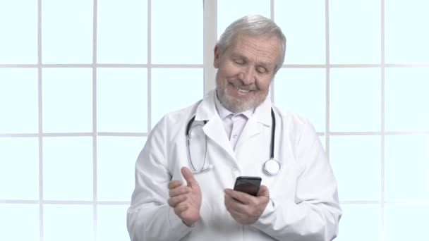 彼のスマート フォンを使用してうれしそうな古い医師. — ストック動画