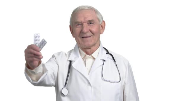 Senior stary lekarz siwe włosy w mundurze, wskazując lek w strip. — Wideo stockowe
