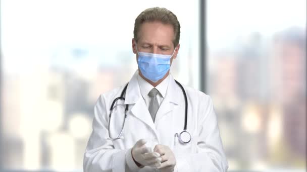 Serious doctor in mask put on gloves. — Stock Video