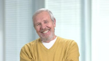 Gülümseyen kıdemli adam kameraya bakan.