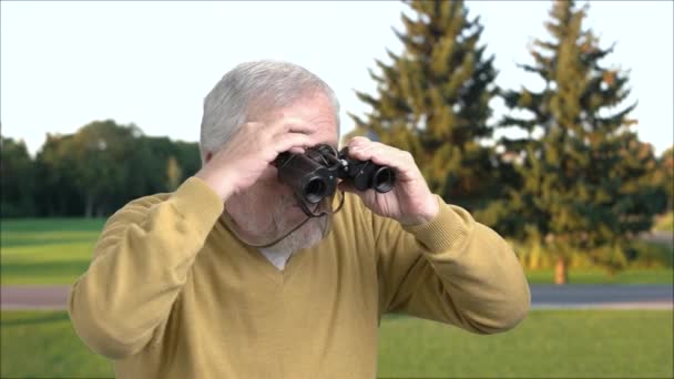 Grandfather with binoculars on nature background. — Stock Video